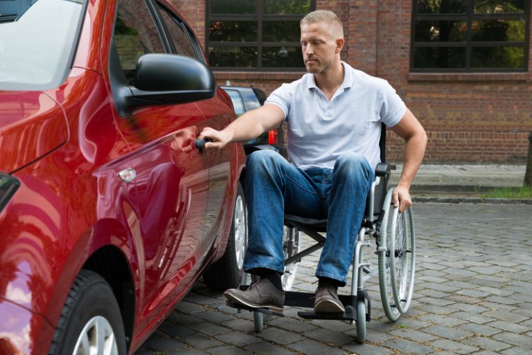 Portrait Of A Handicapped Man Sitting On Wheelchair Opening Door Of A Car